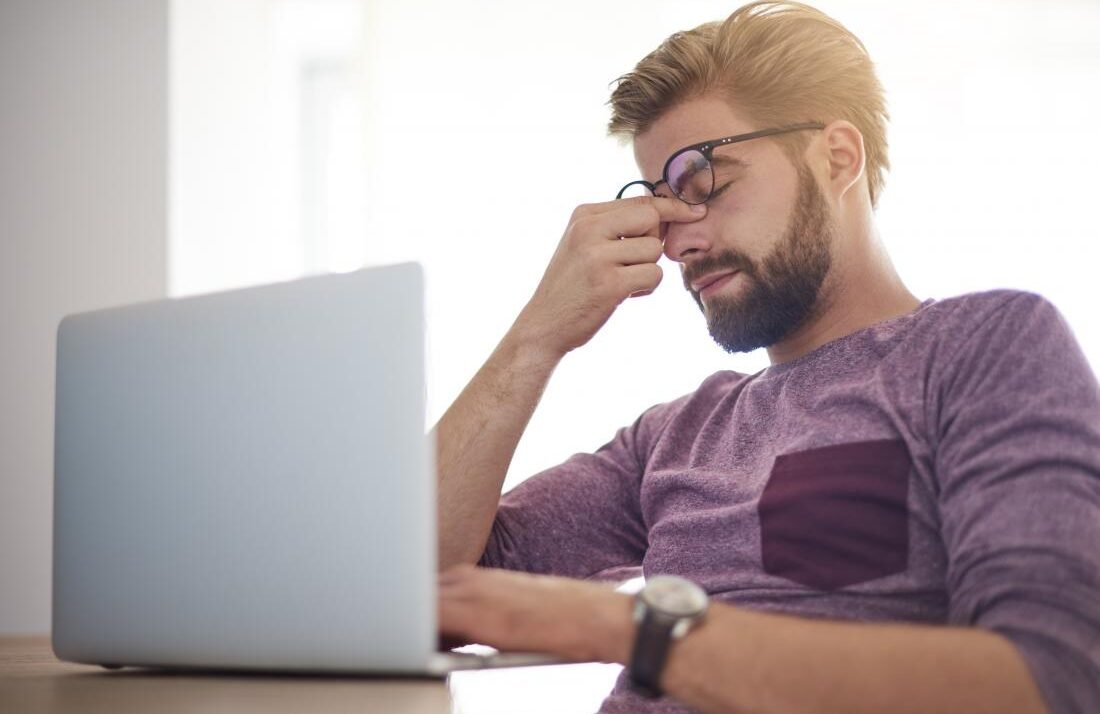 man sitting at computer with tired eyes