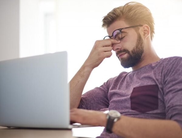 man sitting at computer with tired eyes