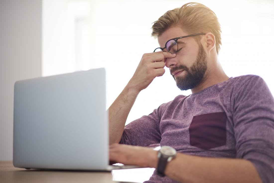 man sitting at computer with tired eyes